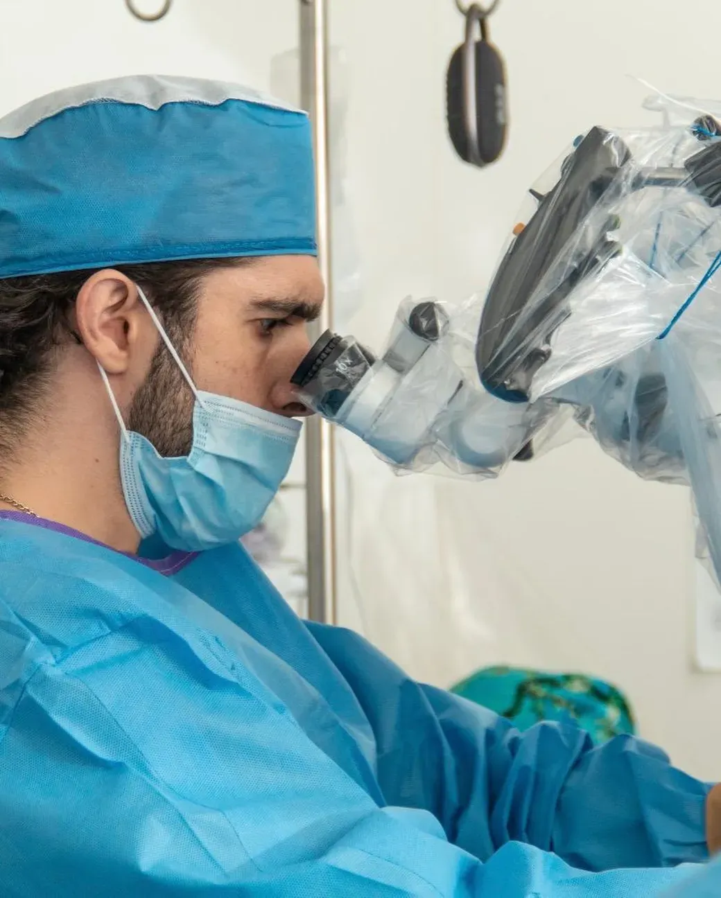 Dr. Adán Soto operando con microscopio quirúrgico